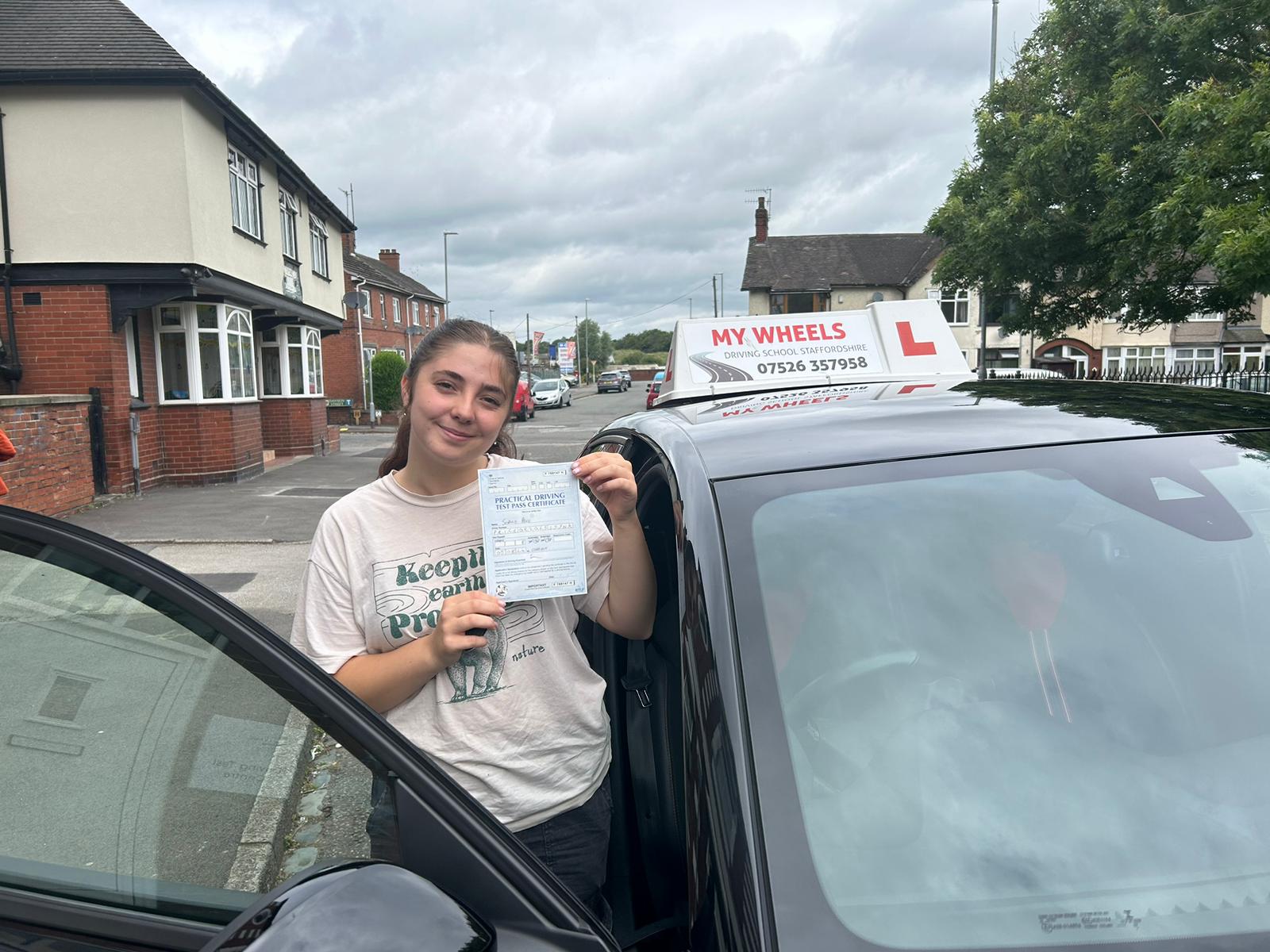 young female holding a driving pass certificate